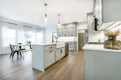 A beautiful, calming farm-style kitchen and dining room with light gray cabinets and white interiors.