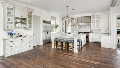 Modern kitchen with white cabinets, large island and dark hardwood flooring.