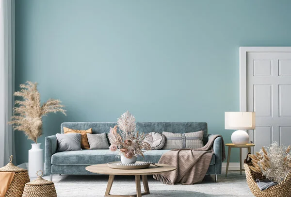 Bright living room interior with walls painted a shade of cyan and couch in front of round coffee table.