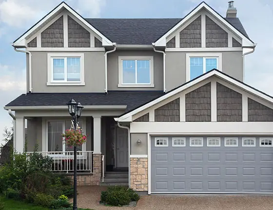 A two story house with grey clapboard and a garage at the front.